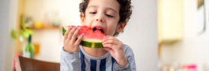 menino pequeno comendo uma melancia