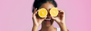 uma mulher segurando duas laranjas nos olhos
