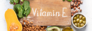 uma placa escrita vitamin E e rodeada de alimentos