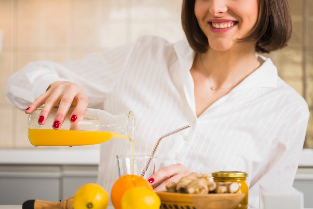 Mulher tomando suco de laranja rico em vitaminas para aumentar a imunidade vitamina A